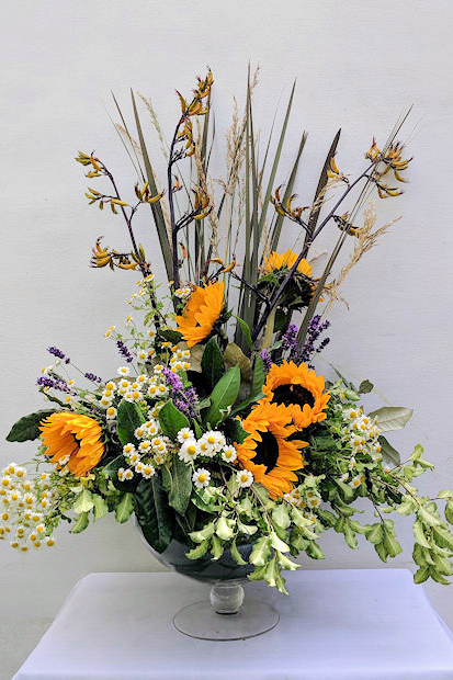 Pedestal arrangement with small sunflowers.