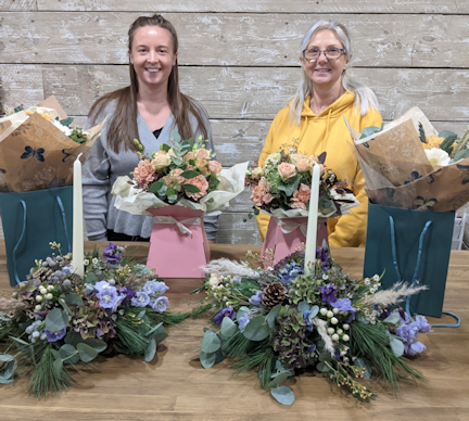 Two participants at a private floristry workshop, showing what they have created.